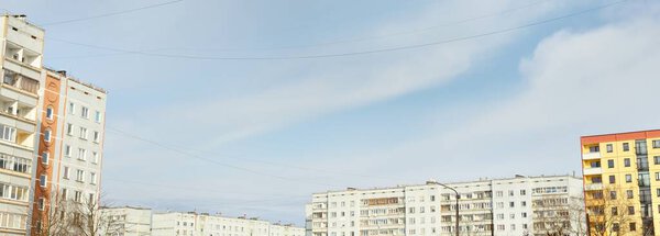 Soviet era block panel houses. Cloudy blue sky, dramatic cloudscape. Panoramic view. Real estate development, architecture, building exterior, construction industry, technology, history, past