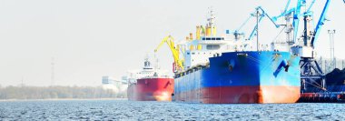 Kömür terminalinde büyük bir kargo gemisi (kargo gemisi), yakın plan. Arka planda iskele vinçleri. Krievu Adası, Riga, Letonya. Yük taşımacılığı, yakıt ve enerji üretimi, çevresel hasar