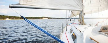 Rüzgardan kanat çırpan yelkenli beyaz bir yat fırtınadan sonra yelken açıyor. Güverteden pruvaya kadar yakın çekim. Boş zaman aktivitesi, spor, eğlence teması. Glomma Nehri, Oslofjord, Norveç