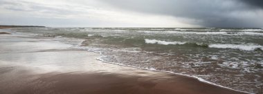 Fırtına sonrası dramatik bulutların altında Baltık Denizi 'nin kumlu sahili. Letonya 'da sızıntı var. Destansı deniz manzarası. Kasırga, fırtına, sert hava, meteoroloji, iklim değişikliği, doğal fenomen