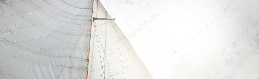 White sails of a sloop rigged yacht against cloudy blue sky. Sailing and rigging equipment. Recreation theme. North sea, Norway