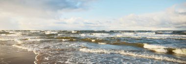 Baltık Denizi 'nin üzerindeki renkli günbatımı bulutları, kışın kasırga. Dramatik gökyüzü, dalgalar ve su sıçramaları. Ekoloji, iklim değişikliği, küresel ısınma kavramları