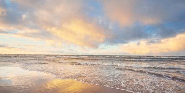 Baltık Denizi 'nin üzerindeki renkli günbatımı bulutları, kışın kasırga. Dramatik gökyüzü, dalgalar ve su sıçramaları. Ekoloji, iklim değişikliği, küresel ısınma kavramları