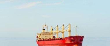 Europoort 'tan denize açılan bir vinçle büyük kırmızı bir yük gemisi (kargo gemisi). Açık mavi gökyüzü ve sirrus bulutları. Rotterdam, Hollanda. Küresel iletişim, lojistik, endüstri teması