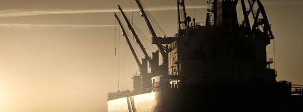 日落时停泊在港口的大型货船 散装货船 后面是起重机 波罗的海 拉脱维亚 货物运输 全球通信 环境破坏 — 图库照片