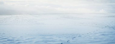 Gün batımında kar fırtınasından sonra karla kaplı arazinin panoramik görüntüsü. Taze karda insan izleri. Buz çölü. Dramatik bulut manzarası. Küresel ısınma teması. Laponya, Finlandiya