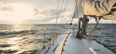 Gün batımında açık denizde yelken açmak. Güverteden pruvaya, direğe ve yelkenlere yakın görüntü. Dramatik fırtınalı gökyüzü, kara bulutlar, kış kasırgası, sert hava. Destansı deniz manzarası. Kuzey denizi, Norveç