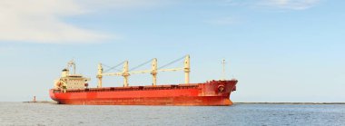 Europoort 'tan denize açılan bir vinçle büyük kırmızı bir yük gemisi (kargo gemisi). Açık mavi gökyüzü ve sirrus bulutları. Rotterdam, Hollanda. Küresel iletişim, lojistik, endüstri teması