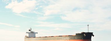 Büyük bir yük gemisi (kargo gemisi) Europoort 'tan açık denizlere açılır. Açık mavi gökyüzü ve sirrus bulutları. Rotterdam, Hollanda. Küresel iletişim, lojistik, endüstri teması
