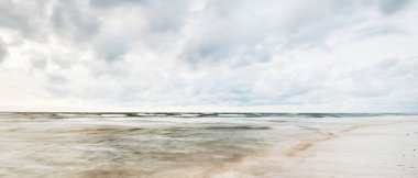 Letonya 'da fırtınadan sonra Baltık Denizi' nin üzerinde epik bir şekilde parlayan günbatımı bulutları. Kumlu sahilden bir manzara. Dramatik deniz manzarası. Kavramsal görüntü, uzun pozlama. Resim gibi bir manzara.