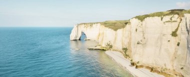 Gün batımında Etretat beyaz uçurumlarının manzaralı panoramik görüntüsü. Dramatik gökyüzü, gök mavisi su. Fransa, Normandiya 'da yaz tatili. Seyahat yerleri, ulusal dönüm noktaları, geziler, tarih.