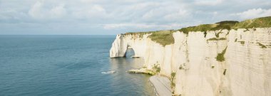 Gün batımında Etretat beyaz uçurumlarının manzaralı panoramik görüntüsü. Dramatik gökyüzü, gök mavisi su. Fransa, Normandiya 'da yaz tatili. Seyahat yerleri, ulusal dönüm noktaları, geziler, tarih.