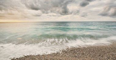 Gün batımında Etretat kayalıklarının yakınındaki kayalık sahil manzarası. Renkli akşam bulutları. Normandiya, Fransa. Dramatik deniz manzarası. Seyahat yerleri, ulusal dönüm noktası, çevresel koruma