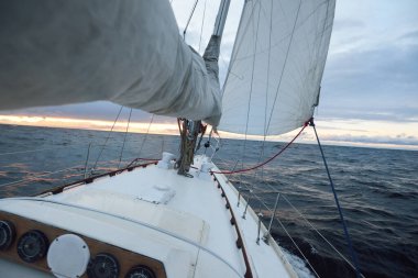 Bir kış günü açık denizde yat gezintisi. Güverteden pruvaya, direğe ve yelkenlere yakın görüntü. Dramatik fırtınalı gökyüzü, kara bulutlar. Destansı deniz manzarası. Kuzey denizi, Norveç