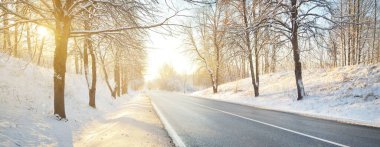 Karla kaplı ormanın içindeki boş otoyolun panoramik görüntüsü. Kırsal kesimde kış manzarası. Seyahat, Noel tatili, lojistik, tehlikeli sürüş, off-road, ulaşım, kış lastikleri, hız, özgürlük