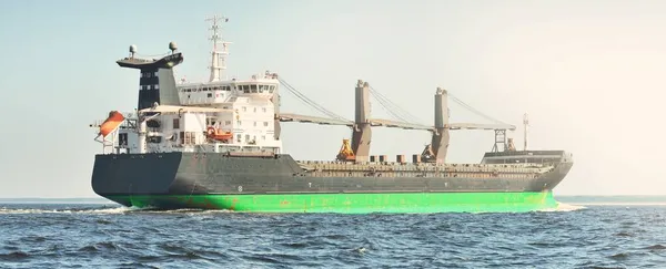 stock image Large bulk carrier (cargo crane ship) sailing in the Baltic sea to Riga port, Latvia. A view from the yacht. Global communications, logistics, industry, freight transportation