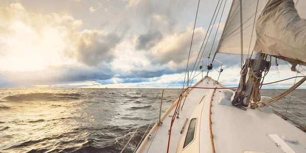 日没の冬の日に屋外の海でヨットセーリング デッキから弓 マスト 帆へのクローズアップビュー 劇的な空 暗い雲を介して黄金の太陽の光 壮大な海の景色 ノルウェー — ストック写真