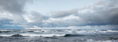 Baltık Denizi 'nin üzerinde kara fırtına var, dalgalar ve su fışkırıyor. Dramatik bulut manzarası. Doğa, çevre, kararsız hava, iklim değişikliği. Atmosferik manzara. Panoramik görünüm, uzun pozlama