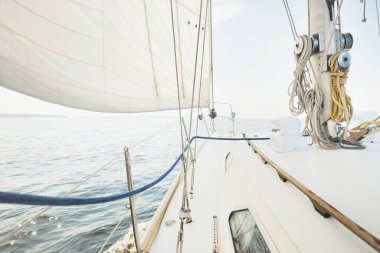 Güneşli bir yaz gününde beyaz bir yat denize açılıyor. Güverteden pruva ve yelkenlere kadar yakın çekim. Dalgalar ve su sıçramaları. Açık mavi gökyüzü. Baltık Denizi, İsveç