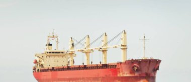 Europoort 'tan denize açılan bir vinçle büyük kırmızı bir yük gemisi (kargo gemisi). Açık mavi gökyüzü ve sirrus bulutları. Rotterdam, Hollanda. Küresel iletişim, lojistik, endüstri teması