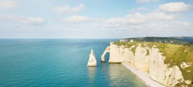 Gün batımında Etretat beyaz uçurumlarının manzaralı panoramik görüntüsü. Dramatik gökyüzü, gök mavisi su. Fransa, Normandiya 'da yaz tatili. Seyahat yerleri, ulusal dönüm noktaları, geziler, tarih.