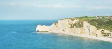 Gün batımında Etretat beyaz uçurumlarının manzaralı panoramik görüntüsü. Dramatik gökyüzü, gök mavisi su. Fransa, Normandiya 'da yaz tatili. Seyahat yerleri, ulusal dönüm noktaları, geziler, tarih.