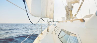 Gün batımında açık denizde yelkenli yelkenli yelkenli. Gökyüzü açık. Güverteden pruvaya bir manzara, direk, yelkenler. Ulaşım, seyahat, gezi, spor, eğlence, boş zaman aktivitesi, yarış, yelkenli yarışı