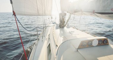 Gün batımında açık denizde yelkenli yelkenli yelkenli. Gökyüzü açık. Güverteden pruvaya bir manzara, direk, yelkenler. Ulaşım, seyahat, gezi, spor, eğlence, boş zaman aktivitesi, yarış, yelkenli yarışı