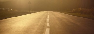 Sıcak bir yaz gününde gün batımında açık bir otoyol. Arka planda orman var. Kırsal alanlarda araba sürmek. Boş zaman aktivitesi, eğlence teması. Letonya