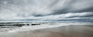Kışın karanlık fırtına bulutlarının altında kuzey denizi, uzun süre açık. Dalgalar ve su sıçramaları. Koyu deniz manzarası. Hollanda 'da. Panoramik görünüm