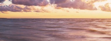 Gök gürültülü bir fırtınadan sonra denizin üstünde destansı pembe gün batımı bulutları. Dramatik bir gökyüzü. Dalgalar ve su dokuya sıçrar. Idyllic deniz manzarası. Kavramsal görüntü, uzun pozlama. Resim gibi bir manzara.