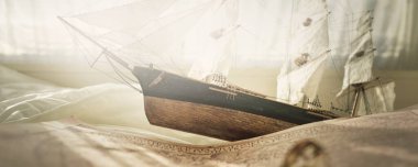 Tahta uzun gemi modeli, eski deniz haritası yakın plan. Klasik natürmort. Yelkencilik, seyahat, koleksiyon, hobi, hatıra, hediye, çocuklar için oyuncak. Oyun odası iç dekorasyonu