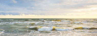 Gün batımında fırtınadan sonra Baltık Denizi. Letonya 'da sızıntı var. Renkli parlayan bulutlar. Dalgalar ve su sıçramaları. Destansı deniz manzarası. Kasırga, fırtına, dönek hava, meteoroloji, ekoloji