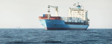 Açık denizde yelken açan bir vinci olan büyük mavi bir kargo gemisi. ABD. Yük taşımacılığı, denizcilik gemisi, küresel iletişim, lojistik, nakliye, dağıtım, sanayi, ticaret, ekonomi