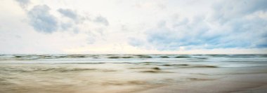 Fırtınadan sonra Baltık kıyıları. Dramatik günbatımı gökyüzü, karanlık parlayan bulutlar, altın güneş ışığı. Dalgalar, su sıçratma. Resimli manzara, deniz manzarası, bulut manzarası, doğa. Panoramik görünüm, uzun pozlama