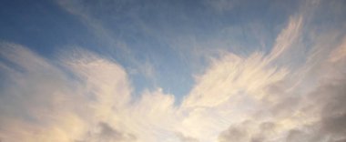 Gün batımında parlayan altın kümülüs bulutlarıyla açık mavi gökyüzü. Yumuşak güneş ışığı. Dramatik bulut manzarası. Sanat, meteoroloji, cennet, barış, grafik kaynakları, resimli panoramik manzara