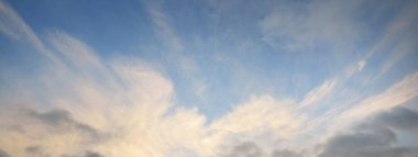 Gün batımında parlayan altın kümülüs bulutlarıyla açık mavi gökyüzü. Yumuşak güneş ışığı. Dramatik bulut manzarası. Sanat, meteoroloji, cennet, barış, grafik kaynakları, resimli panoramik manzara