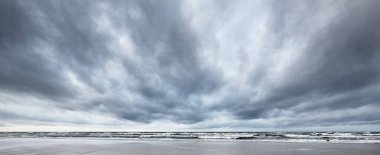 Kışın Kuzey Denizi 'nin yukarısında fırtına bulutları, uzun pozlama. Dramatik gökyüzü, dalgalar ve su sıçramaları. Koyu deniz manzarası. Hollanda
