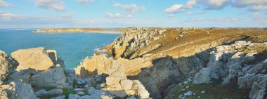 Pointe de Pen-Hir 'in kayalık sahili, uçurumlara yakın. Bulutlu mavi gökyüzü, masmavi su, fırtınalı dalgalar. Dramatik bulut manzarası. Crozon Yarımadası, Britanya, Fransa