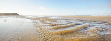 Douarnenez körfezinin kumlu sahilinden bir manzara. Açık mavi gökyüzü. Sudaki yansımalar. Dalgalar ve su sıçramaları. Brittany, Fransa. Seyahat yerleri, boş zaman etkinlik teması
