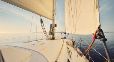 Günbatımında yağmurdan sonra beyaz yat denize açılacak. Güverteden pruvaya kadar yakın çekim. Durgun bir suya yansıyan parlak bulutlarla dolu berrak mavi bir gökyüzü. Idyllic deniz manzarası. Deniz, seyahat, seyahat yerleri