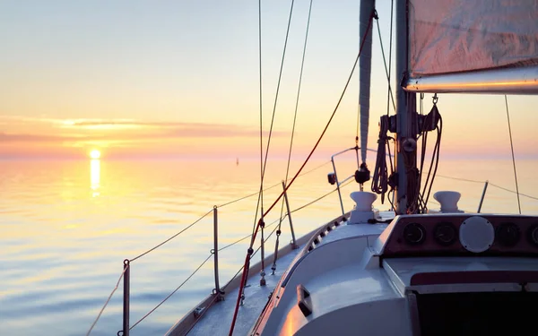 夕日の海で白いヨットセーリング デッキから弓へのクローズアップビュー 澄んだ青い空に輝くピンクの雲が静かな水の中に反映されます 牧歌的な海の景色 クルーズ 旅行先 — ストック写真