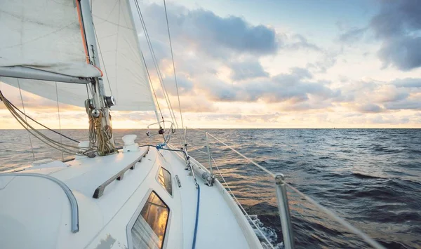 日落时 游艇在开阔的海面上航行 桅杆和帆的近景 雨后的晴空 戏剧性的云彩 金色的阳光 浪花和水花 史诗般的海景 — 图库照片