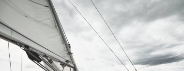 Fırtınada beyaz yat denize açılıyor. Direk görüntüsü, yelkenler, donanım. 9 metre İsveçli seyyar yelkenli. 