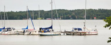 Klasik ve modern yelkenli tekneleri ahşap bir iskeleye (iskeleye) demirlemiş. Yaz tatilleri, dinlenme, boş zaman aktiviteleri. servis, özel gemi. 