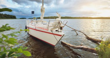 Kayalık kıyıya demir atmış bir yat. 9 metre İsviçre yapımı seyyar yelkenli. Doğa, yaz tatilleri, eğlence, gezi, spor, ulaşım, eko-turizm