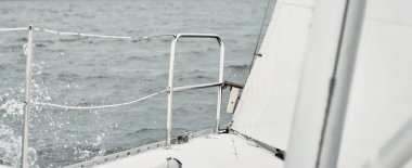 Fırtınada beyaz yat denize açılıyor. Direk görüntüsü, yelkenler, donanım. 9 metre İsviçre yapımı seyyar yelkenli. Yaz tatilleri, dinlenme, spor, boş zaman aktiviteleri.