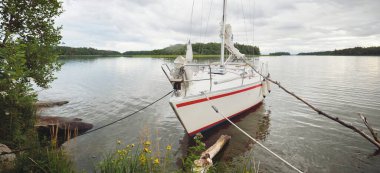 Kayalık kıyıya demir atmış bir yat. 9 metre İsviçre yapımı seyyar yelkenli. İsveç. Doğa, yaz tatilleri, eğlence, gezi, spor, ulaşım, eko-turizm