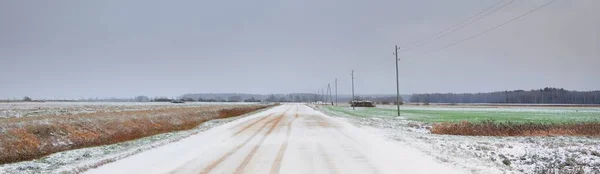 吹雪の後 フィールドを介して雪に覆われた田舎道 送電線 変圧器の棒 車からのパノラマビュー 暗い嵐の空 オフロード 冬のタイヤ リモート村 — ストック写真