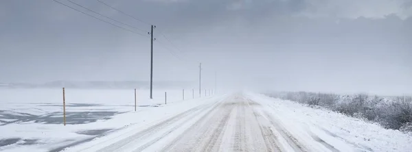 暴风雪过后 覆盖着白雪的乡间小路穿过田野 变压器杆 从车上俯瞰全景 黑暗的暴风雨的天空 冬季轮胎 偏远村庄 — 图库照片